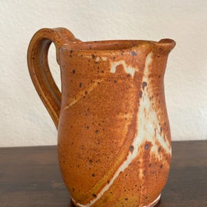 May include: A set of three ceramic mugs with a speckled, matte finish. The mugs are in shades of cream, light gray, and dark gray. Each mug has a simple, minimalist design, perfect for coffee or tea.