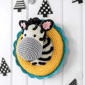May include: A crocheted zebra head wall hanging with a yellow and blue crocheted frame. The zebra has black and white stripes and a gray nose.