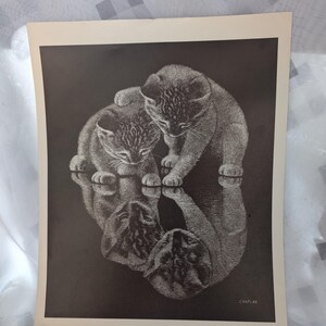 May include: Black and white print of two kittens, one with a paw on the other. The image includes a reflection of the kittens. The print is titled "Pals by Chaplin" and measures 10x13 inches.