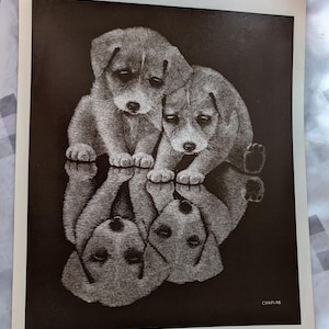 May include: Black and white print of two puppies with a mirrored reflection. The puppies are depicted with detailed shading, creating a textured appearance. The print is titled "Brothers by Chaplan" and is 10x12 inches.