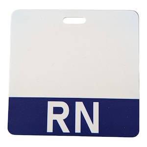 May include: A square white identification badge with rounded corners and a horizontal slot at the top. The bottom third of the badge features a solid dark blue band with the white capital letters RN printed in the centre of the blue section.