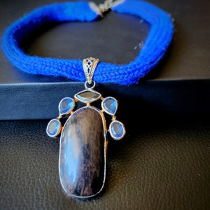 Sterling silver pendant with blue topaz, dinosaur agatized bone fossil, smoky topaz on a hand-knit wool chain/ribbon necklace