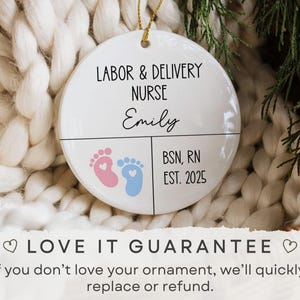 K&ouml;nnte beinhalten: Wei&szlig;er Keramikschmuck mit dem Text "LABOR & DELIVERY NURSE" und dem Namen "Emily". Er zeigt rosa und blaue Babyf&uuml;&szlig;e und den Text "BSN, RN EST. 2025". Der Schmuck h&auml;ngt an einem goldenen Faden.