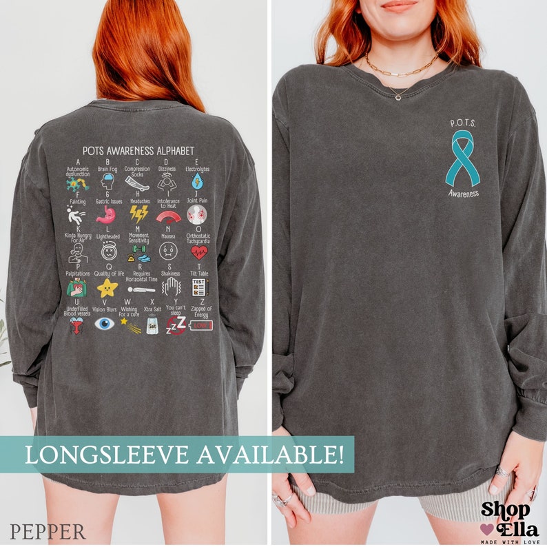 May include: Dark gray long-sleeve shirt with "POTS Awareness" text and a teal ribbon graphic. The back of the shirt features the "POTS Awareness Alphabet" with medical terms and illustrations. The shirt is available in long sleeve.