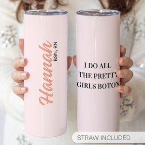May include: Two light pink stainless steel tumblers. One tumbler has the name "Hannah" in a copper script with "BSN, RN" below. The other tumbler has the text "I DO ALL THE PRETTY GIRLS BOTOX" in black. The words "STRAW INCLUDED" are at the bottom.