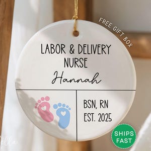 Round ceramic ornament with white background featuring pink and blue baby footprints. Text reads Labor and Delivery Nurse with custom name, credentials, and year. Includes Free Gift Box and Ships Fast.