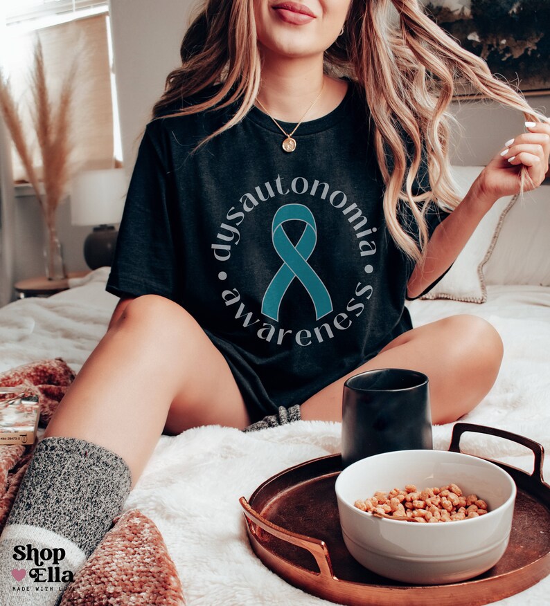 May include: A black t-shirt with a teal ribbon and the text "Dysautonomia Awareness" in a circle.