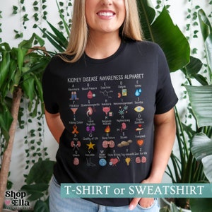 May include: Black t-shirt with a white graphic of an alphabet chart for kidney disease awareness. The chart includes terms like albuminuria, blood pressure, creatinine, dialysis, edema, filtration, glomerulonephritis, hematuria, immunosuppressant, jaundice, kidney cancer, lupus nephritis, metabolic acidosis, nephrectomy, organ donation, PKD, quality of life, renal failure, stones, transplant, uremia, vasculitis, water balance, extra strong yay research, zest for life. The shirt is available as a t-shirt or sweatshirt.