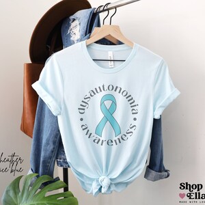 May include: Light blue t-shirt with a teal ribbon and the text "dysautonomia awareness" in a circle.