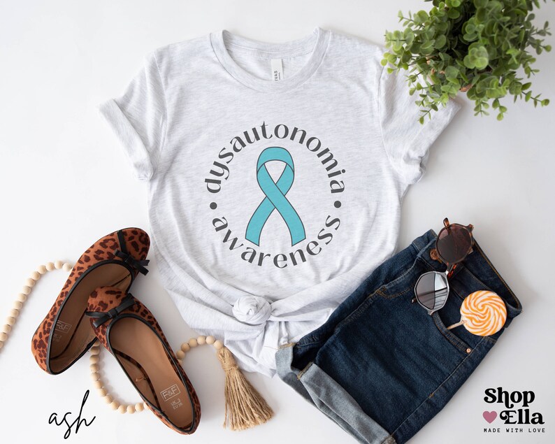 May include: A white t-shirt with a teal ribbon and the text "dysautonomia awareness" in a circle around the ribbon.
