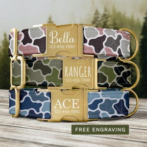 May include: Three pet collars stacked vertically, each featuring a gold-tone metal buckle engraved with a name and phone number. The top collar has a pink and gray cow print, the middle has a green camouflage pattern, and the bottom is blue.