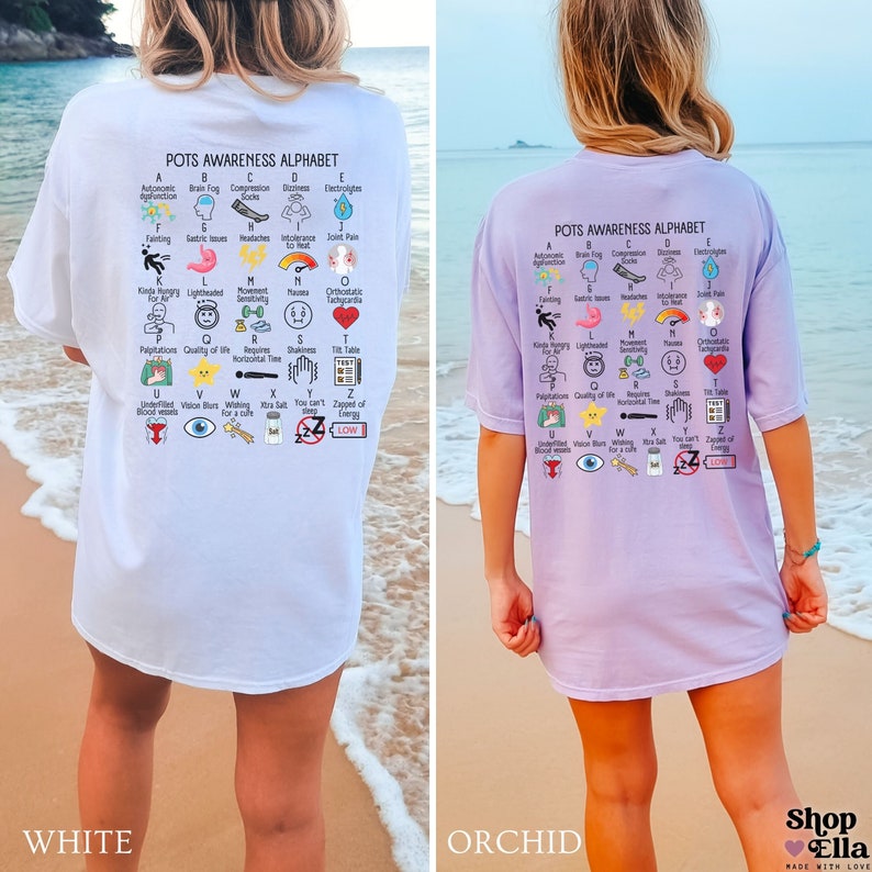 May include: White and orchid-colored t-shirts with the text "POTS Awareness Alphabet" and an illustrated alphabet of POTS symptoms. The shirts are worn by a person on a beach. The text "Shop Ella" is in the bottom right corner.
