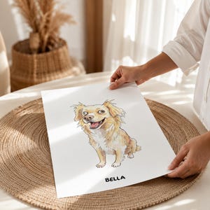 Puede incluir: Una l&aacute;mina rectangular blanca con una ilustraci&oacute;n en acuarela de un perro de pelo largo de color marr&oacute;n claro con expresi&oacute;n alegre, sentado. El nombre BELLA est&aacute; impreso en letras may&uacute;sculas negras en la parte inferior del papel.