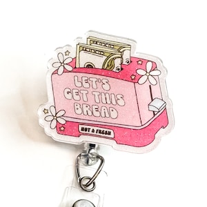 May include: Pink glitter toaster with the text "Let's Get This Bread" and a stack of dollar bills inside. The toaster has a white handle and the text "Hot & Fresh" on the bottom. The toaster is attached to a clear retractable badge reel.