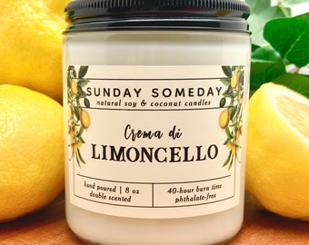 May include: A glass jar candle with a black lid, labelled "Crema di Limoncello." The label includes text: "SUNDAY SOMEDAY natural soy & coconut candles." The candle is surrounded by lemons and greenery. The label also states "hand poured | 227g double scented 40-hour burn time phthalate-free."