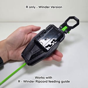 May include: A black and green toy launcher with a green cord. The launcher has the text "BEYBLADE 3 WINDER LAUNCHER" and "R only - Winder Version". The text "Works with R - Winder Ripcord feeding guide" is also visible.