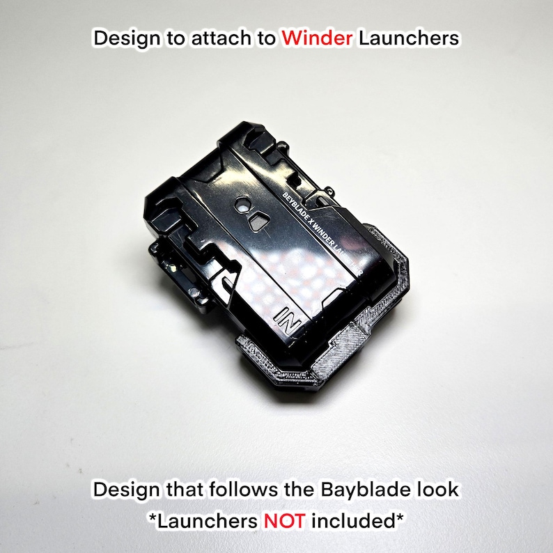 Pu&ograve; includere: Un accessorio in plastica nera progettato per essere fissato ai lanciatori Beyblade X Winder. L'oggetto presenta una superficie testurizzata con il testo "BEYBLADE X WINDER LAUNCHER" e "IN" stampato sulla parte anteriore. Il testo "Design to attach to Winder Launchers" e "Design that follows the Bayblade look *Launchers NOT included*" appare nell'immagine.