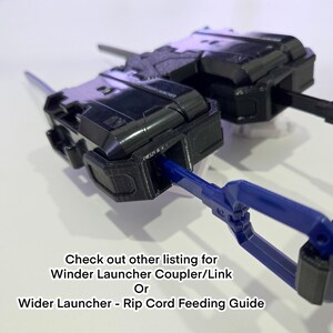 Pu&ograve; includere: Due lanciatori a corda in plastica nera con una corda in plastica blu inserita in uno di essi. Il testo sull'immagine recita: Check out other listing for Winder Launcher Coupler/Link Or Wider Launcher - Rip Cord Feeding Guide.