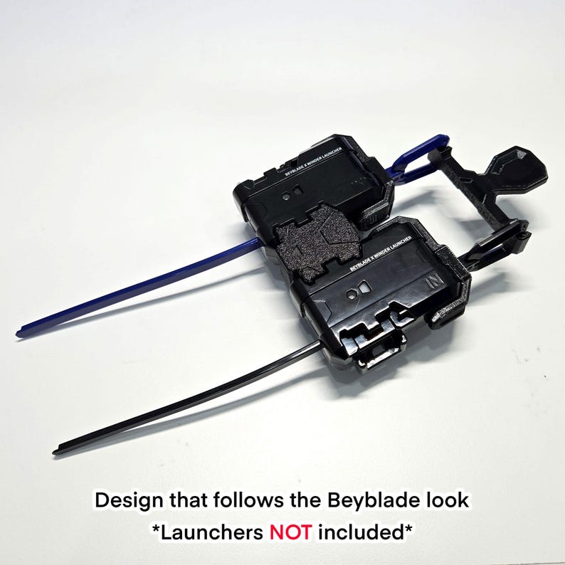 Pu&ograve; includere: Un supporto in plastica nera per lanciatori Beyblade X dal design geometrico. Il supporto presenta due slot per lanciatori e include una striscia di plastica blu e una striscia di plastica nera inserite lateralmente. Il testo BEYBLADE X WINDER LAUNCHER &egrave; stampato sulla superficie.