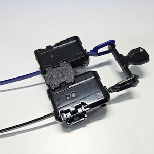 Puede incluir: Dos lanzadores Beyblade X Winder negros con cuerdas azules y negras. Los lanzadores tienen el texto "Beyblade X Winder Launcher" impreso en ellos.