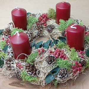 Könnte beinhalten: Ein roter Weihnachtskranz mit vier roten Kerzen, grünem Moos und roten Beeren.