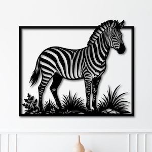 May include: A black and white metal wall art piece showing a zebra standing in tall grass. The zebra is framed in a black square. The artwork is mounted on a white wall above a wooden cabinet.