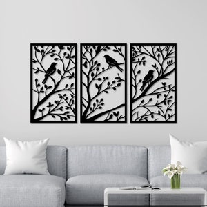 Może przedstawiać: Trzy czarne metalowe panele dekoracyjne na ścianę przedstawiające sylwetkę ptaków siedzących na gałęziach z liśćmi. Panele są prostokątne i mają prosty, nowoczesny design.