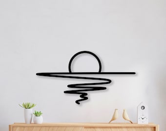 May include: Black metal wall art depicting a stylized sunset over a wavy line representing water. The art is mounted on a white wall above a wooden cabinet with a light wood finish.