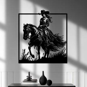 May include: Black metal wall art depicting a woman in a cowboy hat riding a horse. The woman is wearing a long skirt and the horse is in a running pose. The artwork is set against a background of grass.