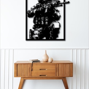 May include: Black and white silhouette of a soldier holding a rifle, framed in a black frame.