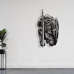 May include: Black metal wall art depicting a kneeling knight holding a sword and shield.