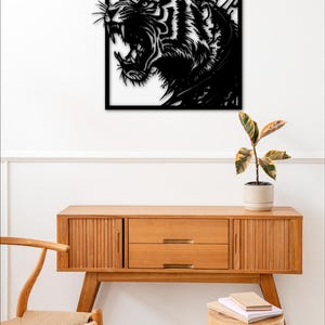 May include: Black metal wall art featuring a roaring tiger head. The art is framed in a square shape and is mounted on a white wall. The tiger's stripes are visible in the design.
