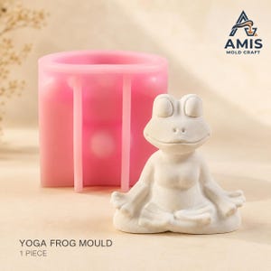 Puede incluir: Un molde de silicona rosa para fundir una rana en posición de yoga sentada, acompañado de una figura de rana blanca terminada. El texto AMIS MOLD CRAFT es visible en la esquina superior derecha y YOGA FROG MOULD 1 PIECE en la parte inferior.