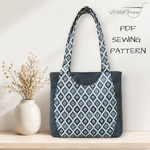 Op de afbeelding: Een donkergrijze tote bag met een zwart-wit geometrisch patroon op de voorkant en handvatten. De tas staat op een houten oppervlak naast een vaas met gedroogde bloemen. De tekst op de afbeelding luidt "PDF SEWING PATTERN".