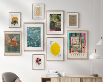 May include: A gallery wall featuring framed art prints with various themes. The collection includes a gold fish, a yellow lemon, a bridge, and a Matisse print. The frames are a light wood color, and the wall is white.
