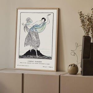 May include: Framed art print featuring a stylized illustration of a woman in a flowing dress, with a blue and green scarf. The artwork is in black and white with a mountain-like shape at the bottom. The print is titled "L'OISEAU D'ARGENT".