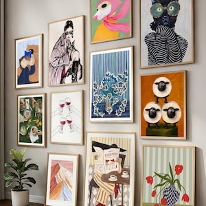 Può includere: Una collezione di stampe artistiche incorniciate con varie illustrazioni. L'opera d'arte comprende una donna con un gatto, un cane con una sciarpa rosa, un gatto con gli occhiali, composizioni floreali e un mucchio di pecore. Le stampe sono in cornici di legno.