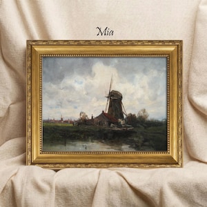 Könnte beinhalten: Gerahmtes Landschaftsgemälde mit einer Windmühle und einem Dorf unter bewölktem Himmel. Das Kunstwerk befindet sich in einem goldenen, verzierten Rahmen. Der Text "Mia" befindet sich über dem Gemälde.