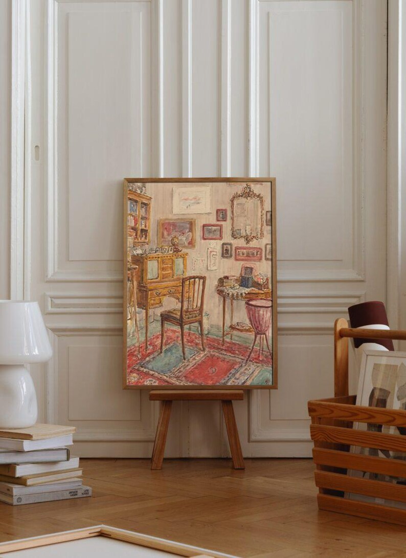 May include: A framed painting of a vintage interior scene, depicting a room with furniture, rugs, and artwork. The painting is displayed on a wooden easel. A white lamp and a wooden crate are in the foreground.