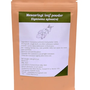Puede incluir: Una bolsa de color beige con una etiqueta verde que muestra "Mesasringi leaf powder (Gymnema sylvestre)". La etiqueta incluye una ilustración de hojas y texto que detalla los ingredientes, el uso y el peso neto: 100 g. La bolsa está sellada.