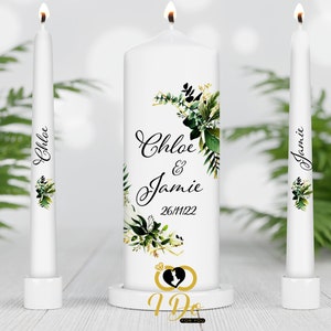 Puede incluir: Vela de unidad blanca con diseño floral verde y los nombres Chloe & Jamie y la fecha 26/11/22. Dos velas blancas más pequeñas con los nombres Chloe y Jamie.