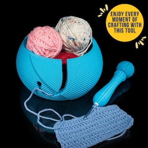 May include: A blue yarn bowl with three balls of yarn, one pink, one white with multi-colored flecks, and one red. A blue yarn needle is on the table next to a blue crocheted piece.