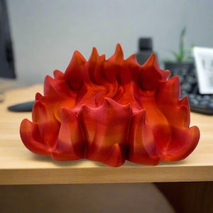 May include: A 3D printed red and orange flame sculpture. The sculpture is made of plastic and has a smooth, glossy finish.