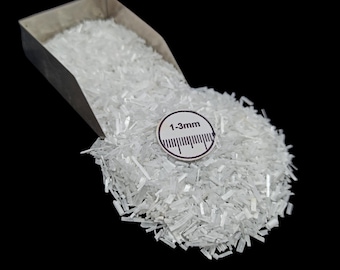 May include: A close-up of a pile of clear, crystalline material, with a scoop partially visible at the top. A small, circular label indicates a size range of 1-3mm. The background is solid black.