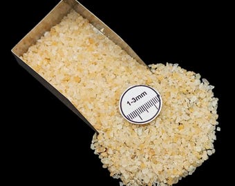 Könnte beinhalten: Nahaufnahme von hellbeige Kies, mit einer Größenangabe von 1-3 mm. Der Kies befindet sich in einer silbernen Metallschaufel und wird auf eine schwarze Oberfläche verschüttet. Der Kies scheint ein natürliches Material zu sein, möglicherweise für Landschaftsbau oder Bastelarbeiten.