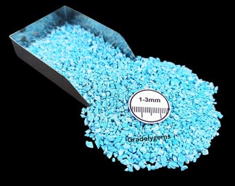 May include: A pile of small, light blue gemstone chips, ranging from 1-3mm in size, spills from a metal scoop. The chips are scattered on a black surface. The text "Gradelygems" and "1-3mm" are visible.