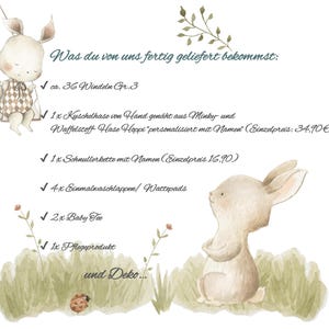 May include: Watercolor illustration featuring two adorable bunny characters and text in German. The text lists items such as diapers, a stuffed bunny, a pacifier chain, washcloths, baby tea, and a care product. The image has a soft, pastel color palette.