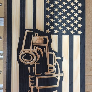 May include: A wooden sign with a black background and a light wood American flag design. The flag has a tractor silhouette in the centre.