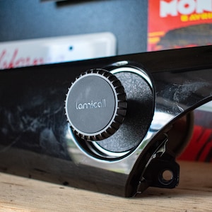 May include: A black car phone mount with a round, black knob and the word "lamicall" printed on it.
