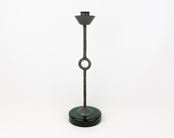 May include: A tall, silver candlestick with a circular ring on the stem and a green glass base.